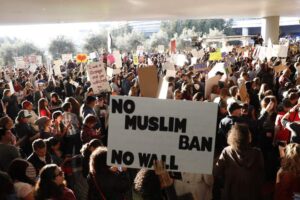 A crowd protesting with the banner which says: NO MUSLIM BAN NO WALL